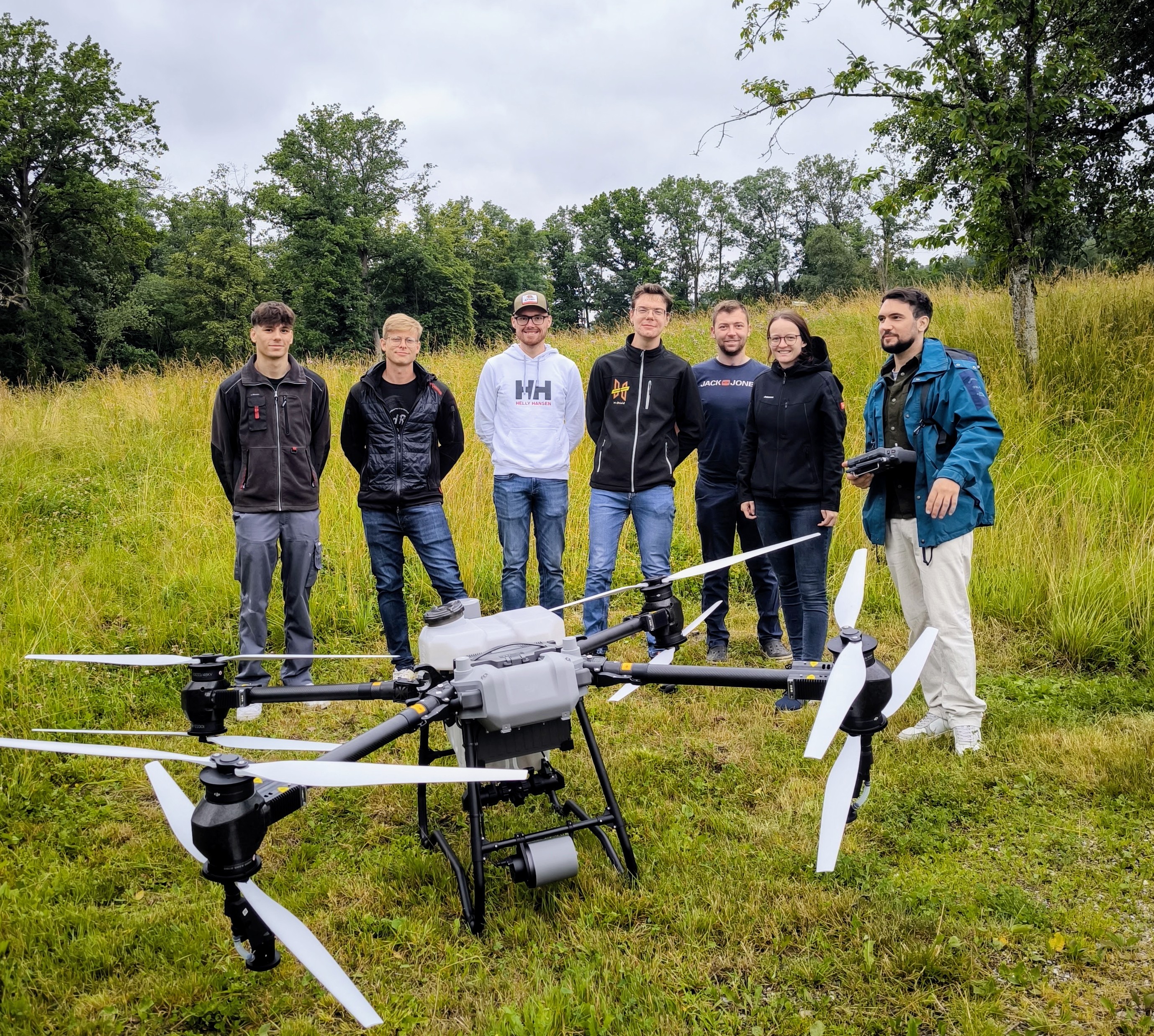 Teilnehmende eines FlightLab-Drohnentrainings mit einer großen Drohne im Freien